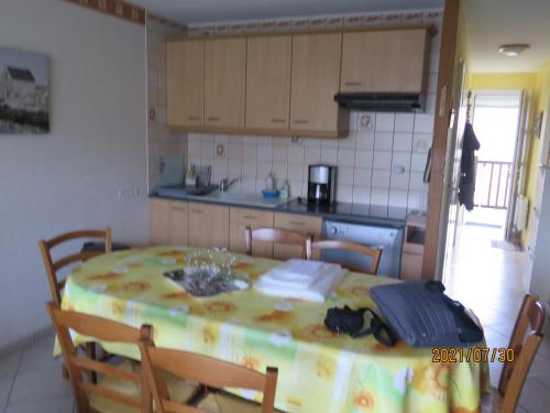 une cuisine avec une table et des chaises dans une pièce dans l'établissement T3 avec balcon plein sud en bord de mer – 50 ml .2 chambres tout confort, équipé de chauffage électrique pour période hivernale,, à Camiers