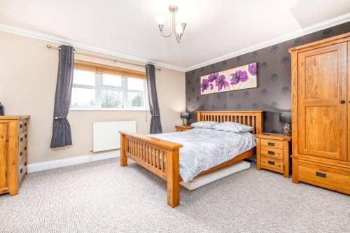 a bedroom with a wooden bed and a window at Detached luxury 5 bed house, lanscaped garden, fire pit, parking, can sleep families or workers in Hockering