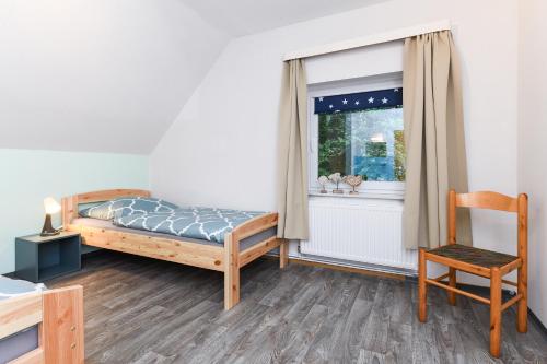 ein Schlafzimmer mit einem Bett, einem Fenster und einem Stuhl in der Unterkunft Ferienhaus Nordseeruhe in Wangerland