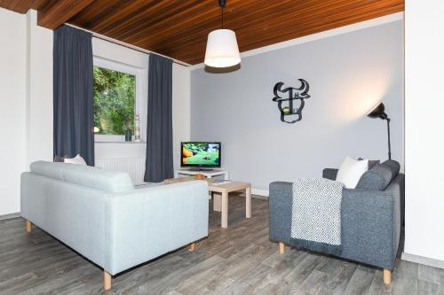 ein Wohnzimmer mit einem Sofa und einem Stuhl in der Unterkunft Ferienhaus Nordseeruhe in Wangerland