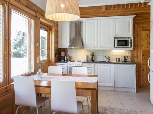 eine Küche mit weißen Schränken sowie einem Tisch und Stühlen in der Unterkunft Holiday Home Tinttityy by Interhome in Tahkovuori