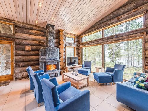 a living room with blue chairs and a fireplace at Holiday Home Jussis chalet b by Interhome in Kuusamo