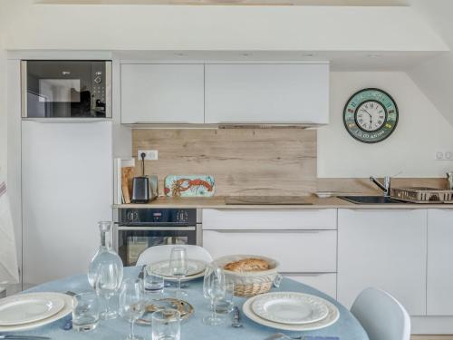 une cuisine avec une table, des verres à vin et une horloge dans l'établissement Apartment Fleurs d'Ajoncs by Interhome, à Saint-Malo