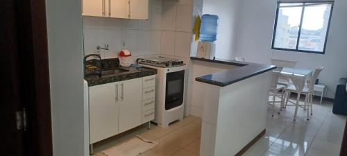 a kitchen with white cabinets and a stove top oven at Pajuçara Maceio Pé na Areia in Maceió