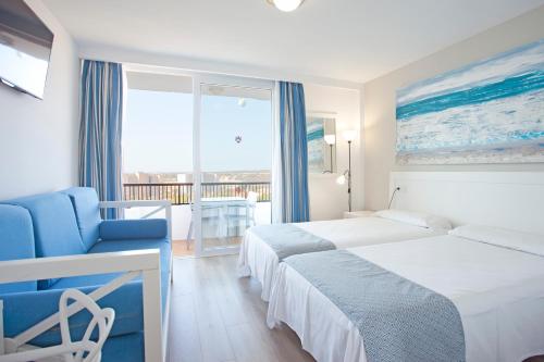 Una habitación de hotel con dos camas y una silla azul. en HYB Eurocalas, en Calas de Mallorca