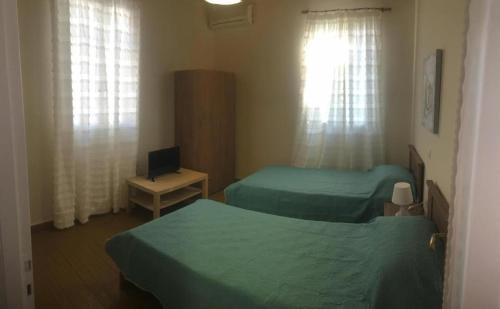 a room with two beds and a desk with a television at Kontos-Traditional house in Andros beach in Andros