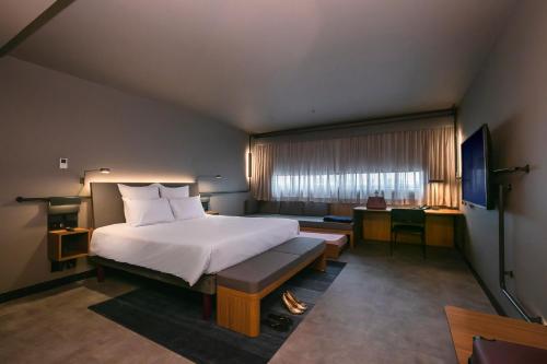 a bedroom with a bed and a desk and a window at Novotel Lencois Paulista in Lençóis Paulista