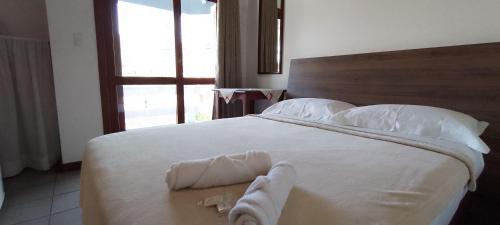 a bedroom with a large white bed with towels on it at Residencial da Praça Garopaba in Garopaba