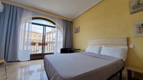 1 dormitorio con cama y ventana grande en Hostal Martes Cáceres Plaza Mayor - Tercer piso SIN ascensor en Cáceres