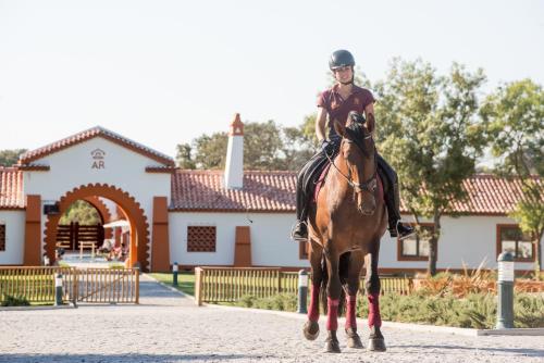 a man riding a horse in front of a house at Vila Gale Collection Alter Real - Resort Equestre, Conference & Spa in Alter do Chão