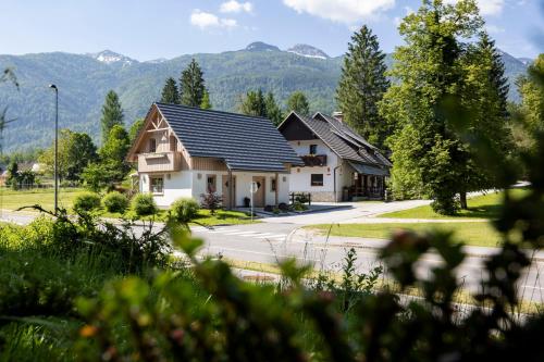 une maison avec des montagnes en arrière-plan dans l'établissement Apartments Alp, à Bohinj