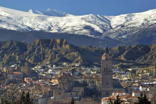 a city with a town with snow covered mountains at Casa La Lonja de Guadix in Guadix