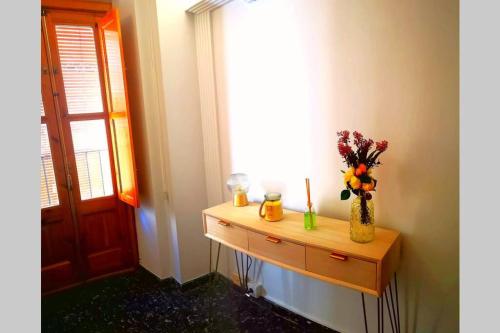 a table with a vase of flowers and a window at Casa La Lonja de Guadix in Guadix
