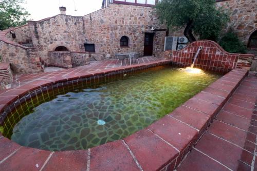 a pool with a water feature in a yard at Hotel Monasterio de Rocamador in Almendral