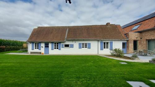 uma casa com um relvado verde em frente em Au Chant des Oiseaux em Tournai