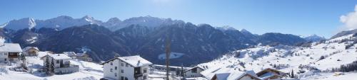 a snow covered mountain with houses and mountains in the background at Apart-Hotel Alpinsonnenresidenz in Fiss