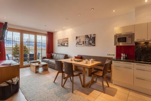 a kitchen and living room with a table and a couch at Apart-Hotel Alpinsonnenresidenz in Fiss