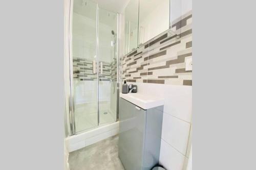 a white bathroom with a shower and a sink at Appartement cosy avec jardin chaleureux in Laon