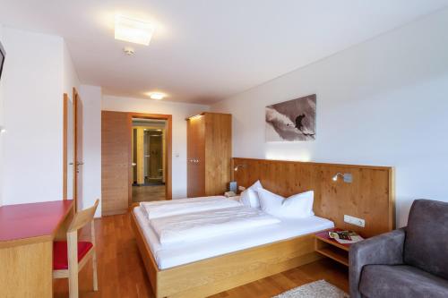 a bedroom with a white bed and a couch at Apart-Hotel Alpinsonnenresidenz in Fiss