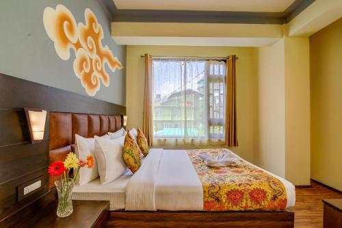 a bedroom with a bed with a vase of flowers at Muscatel Grand Silkroute - 300 Mts from MG Marg in Gangtok