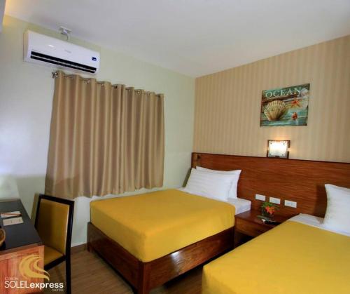 a hotel room with two beds and a desk at Coron Soleil Express Hotel in Coron