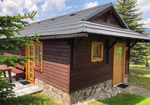 a small wooden cabin with a slate roof at Chata 107 Tatralandia Village in Liptovský Mikuláš