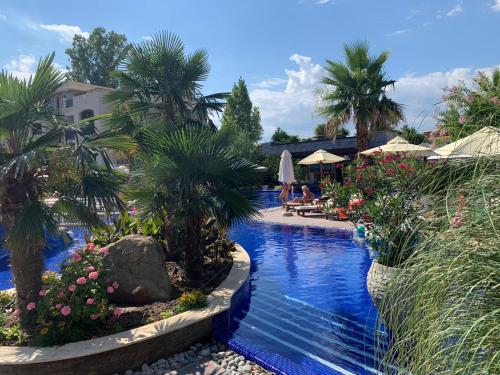 a pool at a resort with palm trees and people sitting at Luxury Orchid apartment with a garden in a private hotel complex Cascadas Bulgaria in Sunny Beach