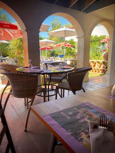 un patio extérieur avec tables, chaises et parasols dans l'établissement Domaine de la Terrasse, à Carbonne