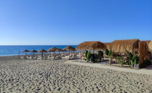 a beach with chairs and umbrellas and the ocean at Hotel Perla del Sur in Torremolinos