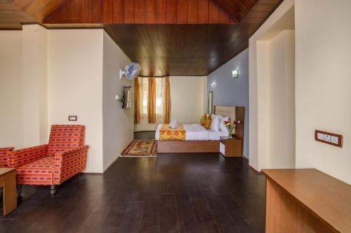 a bedroom with a bed and a chair in a room at Muscatel Grand Silkroute - 300 Mts from MG Marg in Gangtok