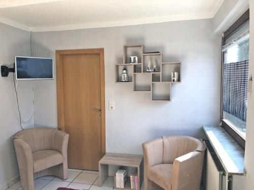 une chambre avec deux chaises, une table et une télévision dans l'établissement An der Allee 7 App, à Dahme