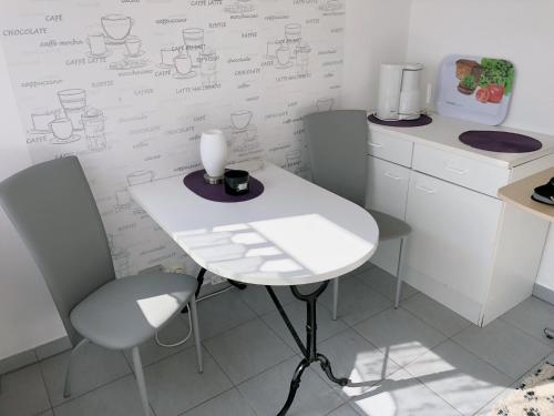 une table et des chaises blanches dans une cuisine avec un bureau sur le mur dans l'établissement An der Allee 7 App, à Dahme