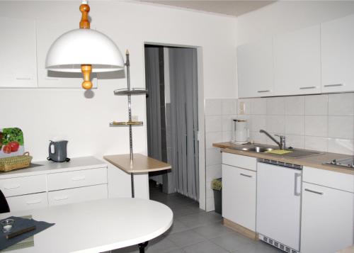 a kitchen with white cabinets and a white table at An der Allee 7 App in Dahme