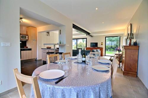 une salle à manger avec une table avec des assiettes et des verres à vin dans l'établissement GITE ROSCLEDAN contemporain, 3 chambres idéalement situé, à Arradon