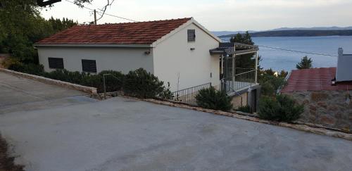 a white house with a driveway in front of the water at Apartmani STJEPAN in Zavala