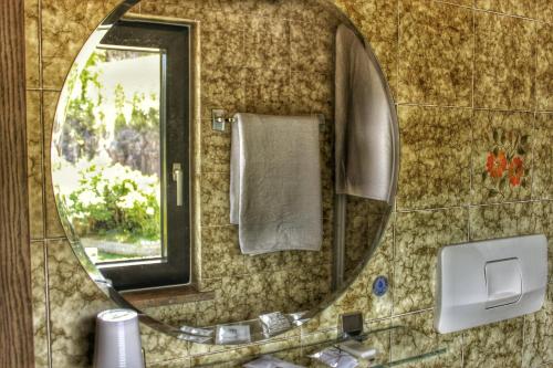 a bathroom with a round mirror and a sink at Panoramahotel Unterinnerhof in Auna di Sotto