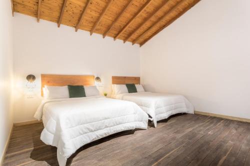two beds in a room with white walls and wood floors at Soy Local Primavera in Medellín