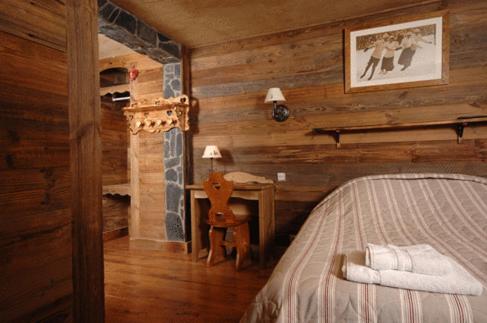 een slaapkamer in een blokhut met een bed en een bureau bij Arc en Ciel in Châtel