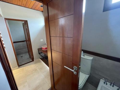 a bathroom with a wooden door and a toilet at Casa en Los Castaños, Tafí del Valle in Tafí del Valle