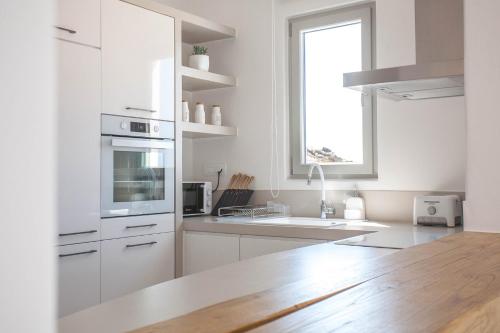 a white kitchen with white cabinets and a window at Bellevue Villas in Plaka
