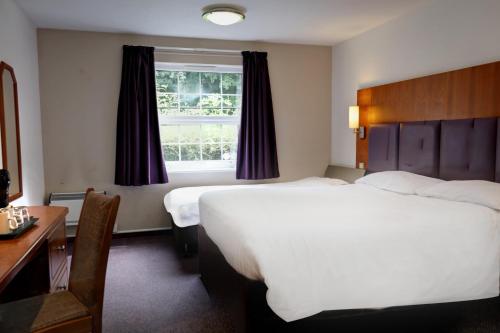 een hotelkamer met 2 bedden, een bureau en een raam bij Orchid Epsom; Sure Hotel Collection by Best Western in Epsom