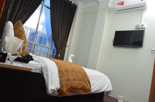 a hotel room with a bed and a tv at Grand Holiday Hotel in Mingora