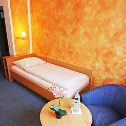 a bedroom with a bed and a table with a bottle on it at Hotel Graf Lehndorff zur Messe in Munich