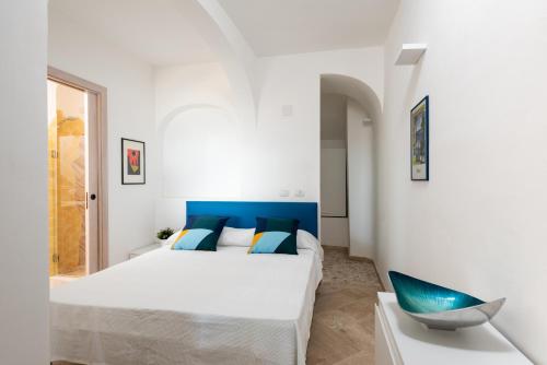 een witte slaapkamer met een bed en een blauw hoofdeinde bij Sherden suites - Your House in Sardinia in Golfo Aranci