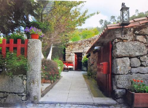 a stone house with a red fence and a sidewalk at Casas Da Ribeira in Seia