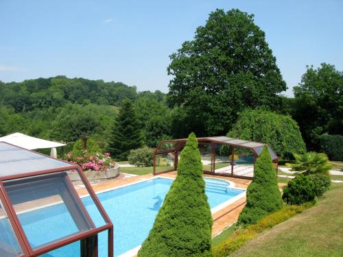 une piscine dans un jardin avec des arbres et un pavillon dans l'établissement Domaine Rêve Normand Honfleur 10 pax, à Genneville