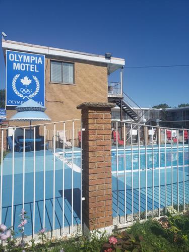a hotel with a fence next to a swimming pool at Olympia Motel in Niagara Falls
