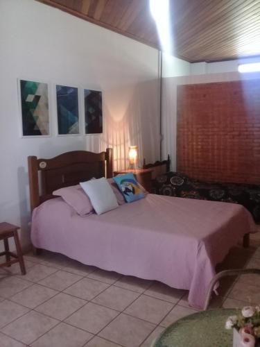 a bedroom with a large bed with purple sheets and pillows at Eco Pousada Sinhá Ruth - Um Refúgio Natural em frente a Represa! in Brotas