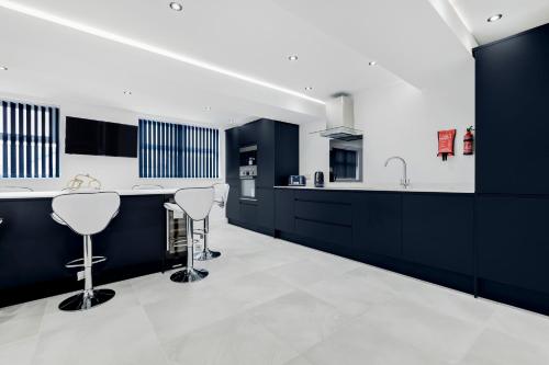a kitchen with black and white counters and stools at Wellington Suites by Sasco Apartments in Blackpool