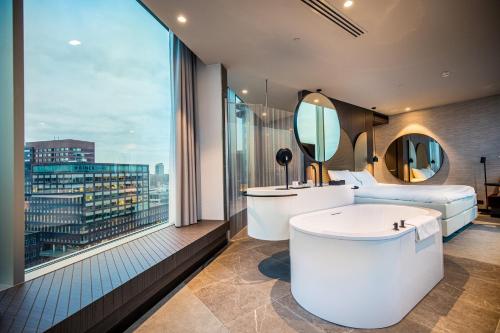 アムステルダムにあるVan der Valk Hotel Amsterdam Zuidas -Raiのバスルーム(バスタブ付)、大きな窓が備わります。